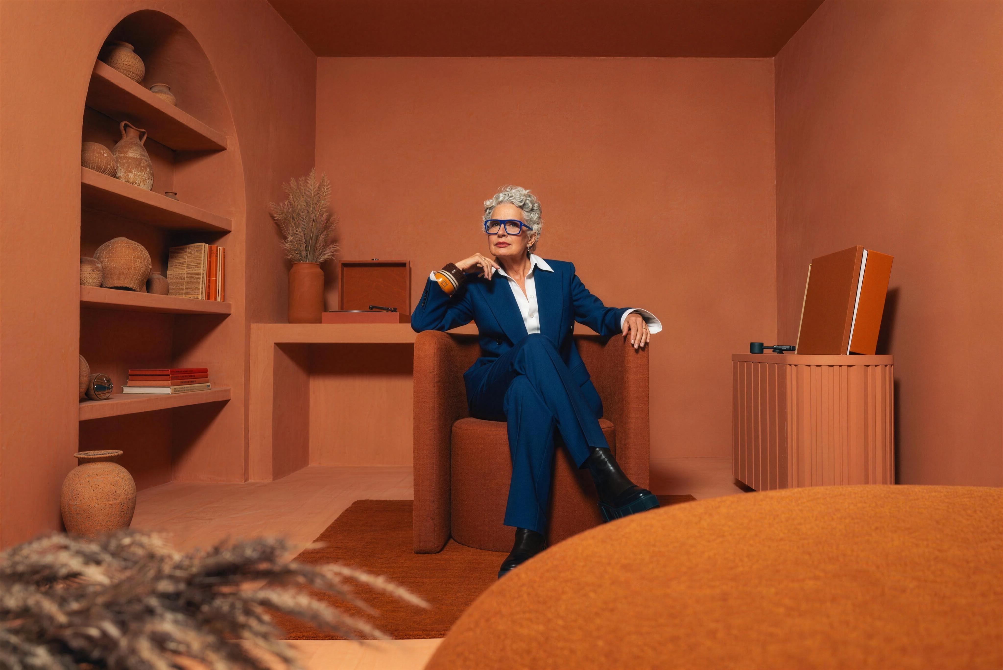 Een vrouw in een blauw pak in een warm terracotta interieur